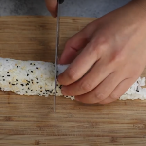 this image shows rollig all the ingredients into a tight sushi roll Using a bamboo mat