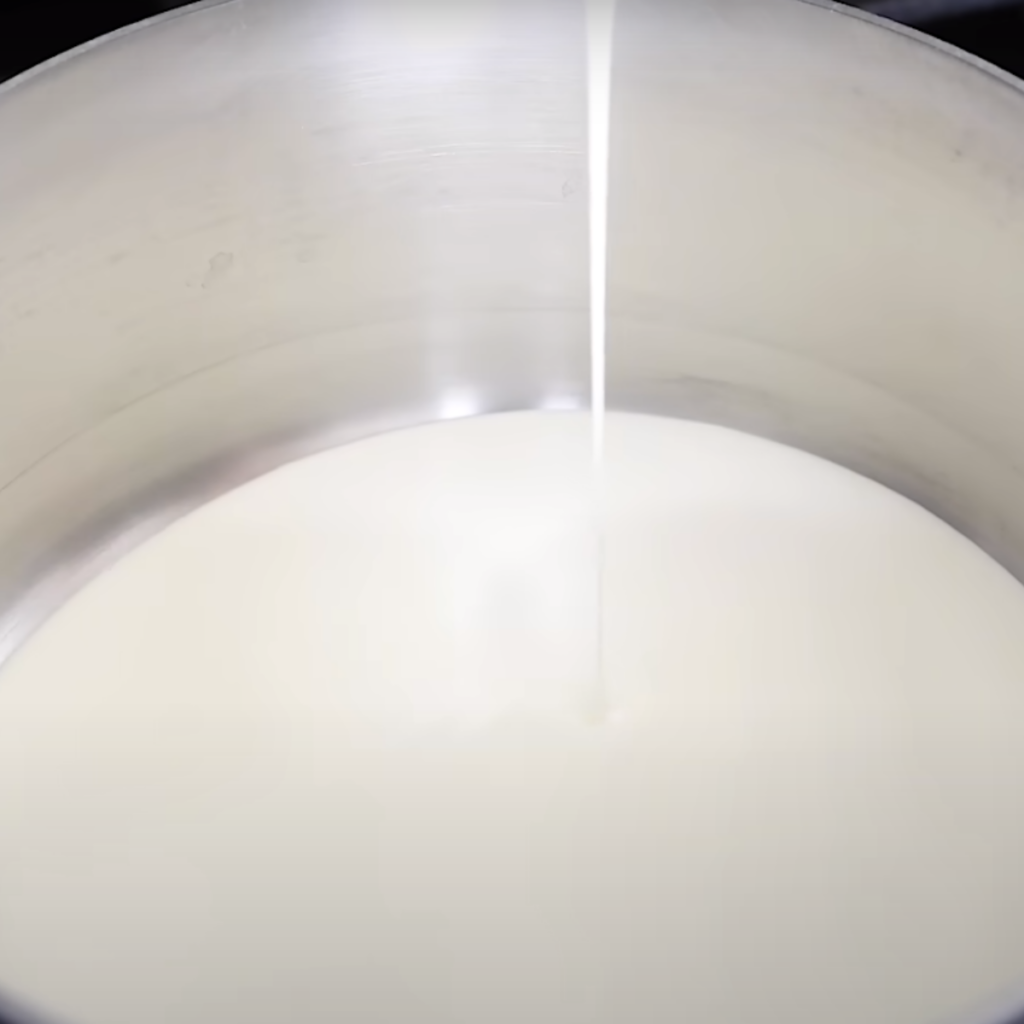This Image shows the pouring heavy cream and milk into a saucepan.